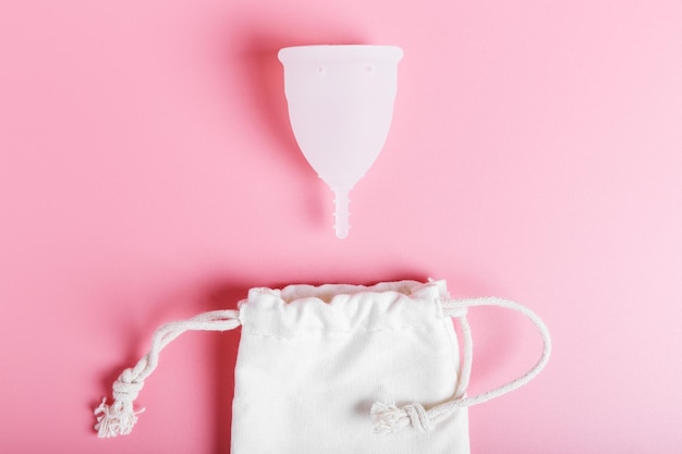 Foto wiederverwendbare weiße menstruationstasse und öko-tasche aus baumwolle auf rosa hintergrund ökologie- und recyclingkonzept zero waste women39s hygiene menstruation kritische tage
