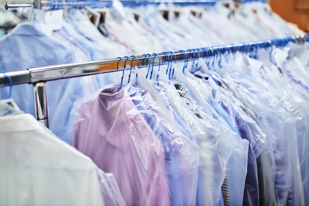 Wiegt saubere Kleidung auf Kleiderbügeln und verpackt sie in Plastiktüten in der chemischen Reinigung