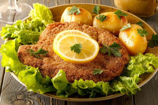 Wiener schnitzel com batatas e salada, foco seletivo.