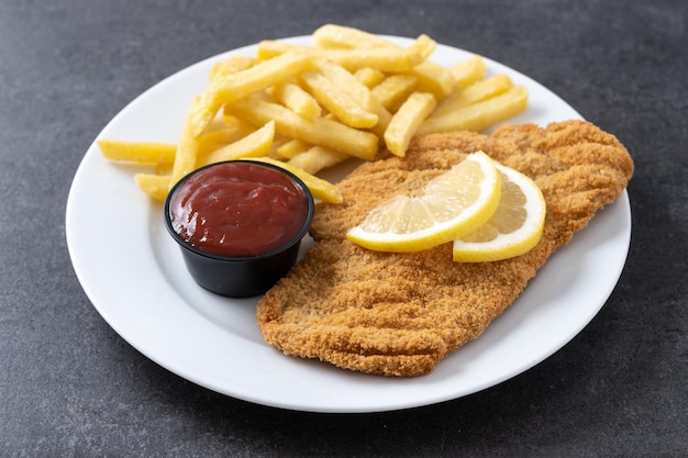 Wiener schnitzel com batatas fritas na superfície de ardósia preta comida vienense típica