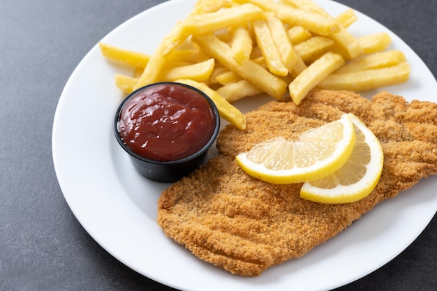 Wiener Schnitzel mit Bratkartoffeln auf schwarzer Schieferplattetypisch wiener Küche