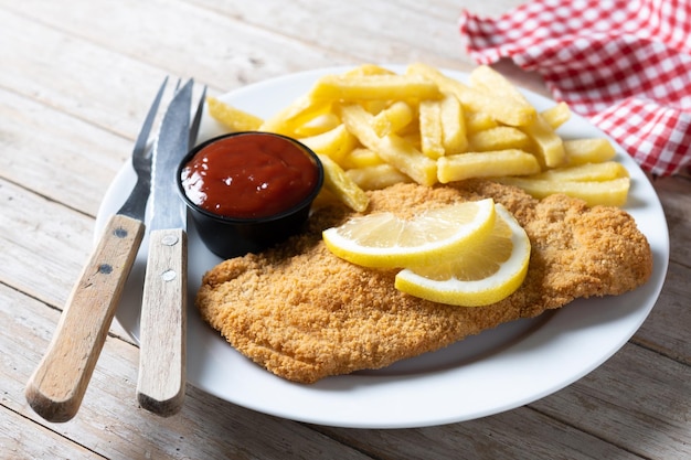 Wiener schnitzel con patatas fritas sobre mesa de madera