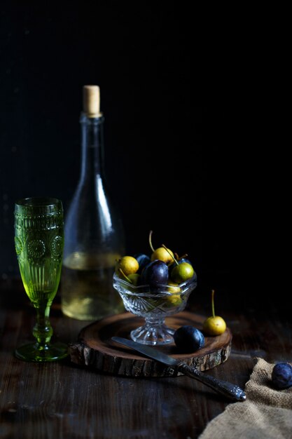 Wilde Birne und Pflaume in einer Glasschale, einem Glas und einer Flasche hausgemachtem Birnenwein