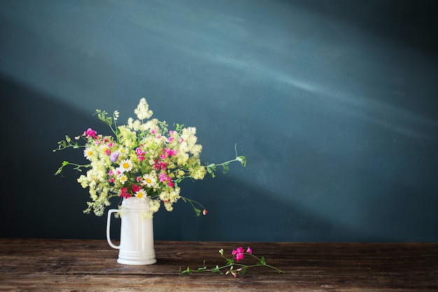 Wilde Blumen im weißen Krug auf dunklem Hintergrund