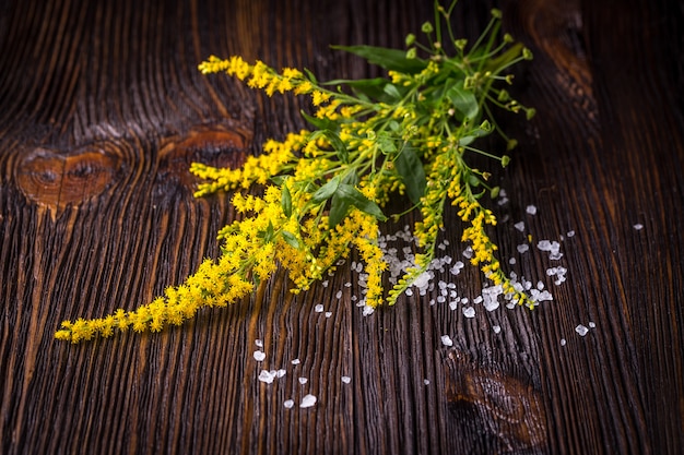 Wilde Blumen und Salz auf Holztisch