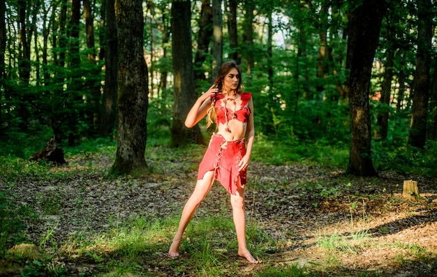 Wilde Frau im Wald Waldfee Lebendes wildes Leben unberührte Natur Sexy Mädchen frühe Stufe in der evolutionären Entwicklung Kultur des wilden Menschen Mode primitives Design Weiblicher Geist Mythologie