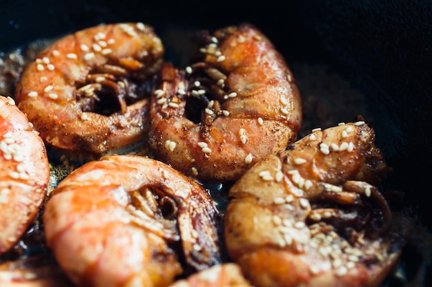 Wilde rote argentinische Garnelen gebraten in der Pfanne in Butter mit Knoblauch und Sesam Draufsicht