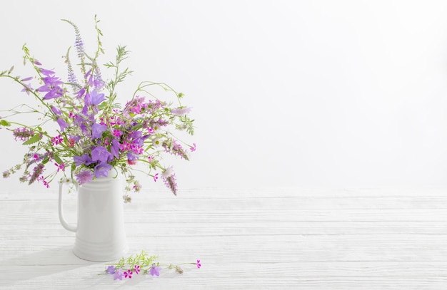 Wilde Sommerblumen im weißen Krug auf weißem Hintergrund