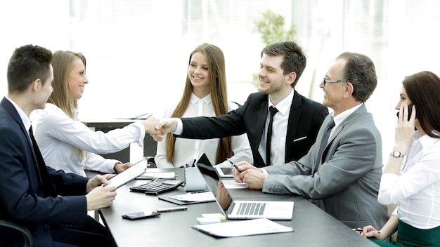 Willkommener Handschlag der Geschäftspartner am Verhandlungstisch im Büro.