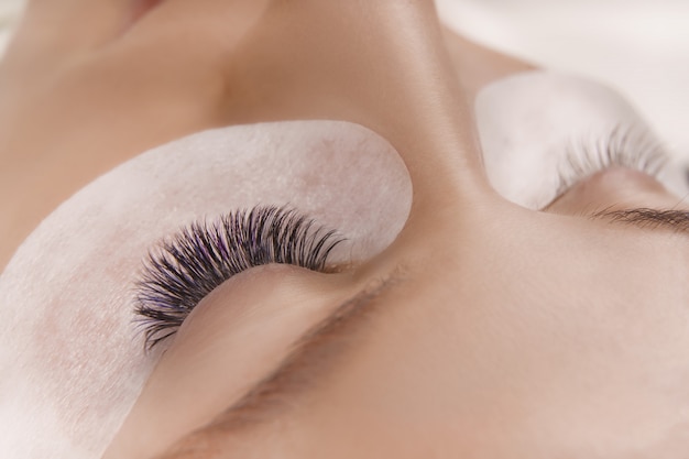 Wimpernverlängerungsverfahren. Nahaufnahme des schönen weiblichen Auges mit langen Wimpern, glatte gesunde Haut.
