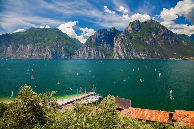 Windsurfistas no identificables surfeando en un lago de Garda cerca de Torbole y Riva del Garda, Italia