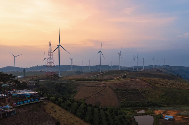 Windturbinen alternativer Energie mit sauberen und erneuerbaren Energien auf Hügeln in landwirtschaftlichen Feldern am Abend