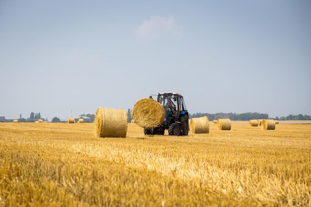 WinnizaUkraine Juli 262016riesiger Traktor sammelt Heuhaufen auf dem Feld an einem schönen blauen sonnigen TagTraktor sammelt StrohballenAgrarmaschine sammelt Heuballen Konzept