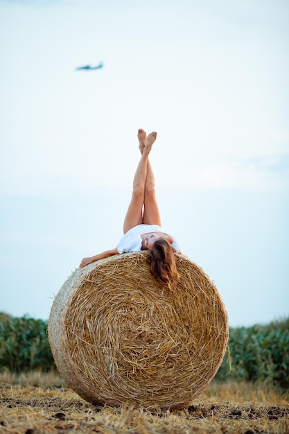 Winnyzja Ukraine 20. Juli 2022 EIN Mädchen liegt auf Strohballen und schaut in den Himmel, im Hintergrund fliegt ein Flugzeug