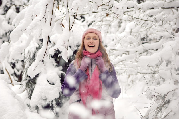 Winter-emotionale Frau mit rosa Hut amüsiert sich im Wald mit Schnee