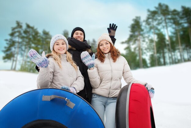 Winter-, Freizeit-, Sport-, Freundschafts- und Personenkonzept - Gruppe lächelnder Freunde mit Schneeschläuchen, die im Freien mit den Händen winken