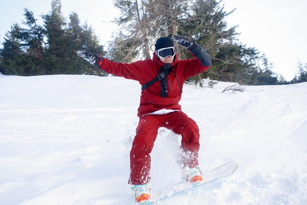 Winter-, Freizeit-, Sport- und Menschenkonzept - Aktiver Snowboarder springt an einem sonnigen Tag in den Bergen. Snowboarden-Nahaufnahme. Skigebiet Sheregesh