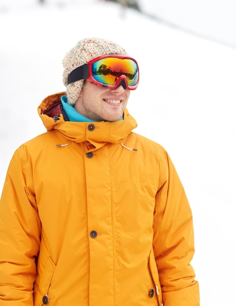 Winter-, Freizeit-, Sport- und People-Konzept - glücklicher junger Mann mit Skibrille im Freien