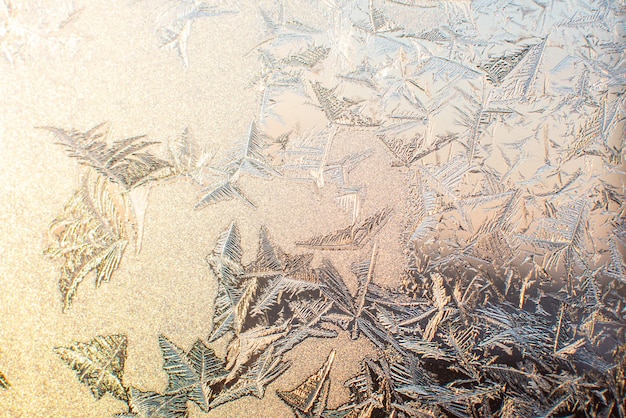 Winter-frostiger Hintergrund. Gefrorene Schneeflocken zeichnen auf dem Fenster. Hauptmotiv ist unscharf