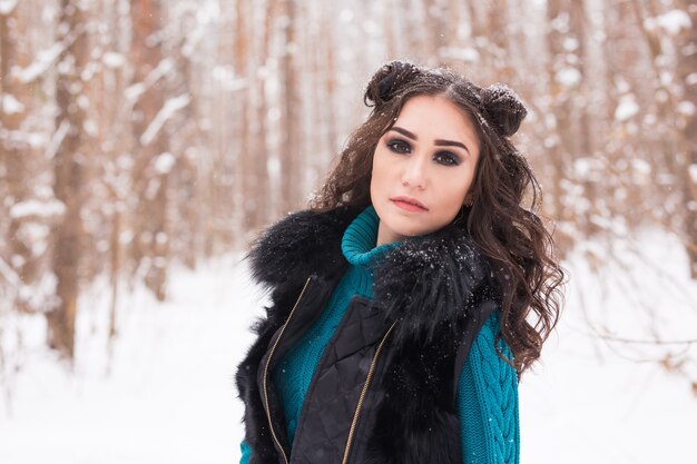 Winter-, Jahreszeit- und Personenkonzept - Junge hübsche Frau, die im verschneiten Park geht