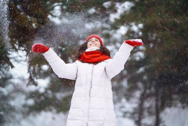 Winter lächelnde Frau in rotem Hut posiert in einem verschneiten Park Kaltes Wetter Mode Winterurlaub