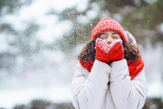 Winter lächelnde Frau in rotem Hut posiert in einem verschneiten Park Kaltes Wetter Mode Winterurlaub