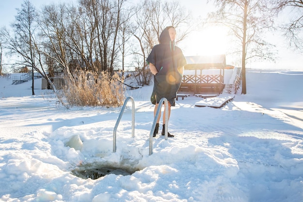 Winter-Schwimmvorbereitung Mann steht an einem frisch geschnittenen Eishöhl am verschneiten See.