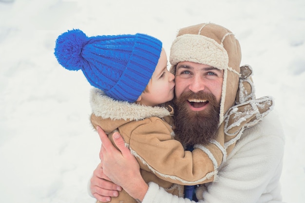 Winter-Vater und Sohn spielen Papa und Junge im Freien, die sich am Morgen vor Weihnachten küssen und umarmen ...