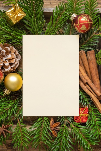 Winter-Weihnachtskomposition mit einer leeren Karte, Tannenzweigen und Dekorationen auf Holztisch. Draufsicht der Weihnachts- und Neujahrsgrußkartenschablone. Urlaubsmodell