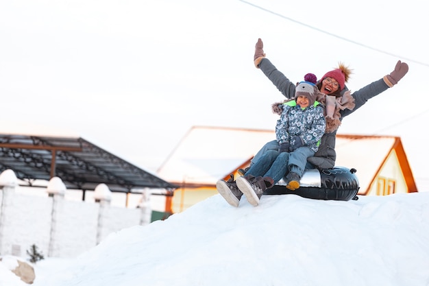 Winteraktivität für Mutter und Kind der Familie, Rutsche vom Schneehügel