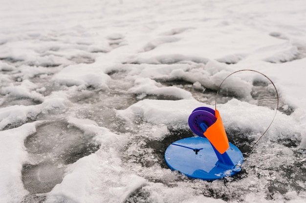 Winterangeln auf Hecht auf dem nachgemachten Fisch auf dem zugefrorenen See Kleines Gerät zum Winterangeln auf dem Eisteich Aufrollrolle für einen Fisch In das Eisloch setzen Sie Gerät mit einer Flagge