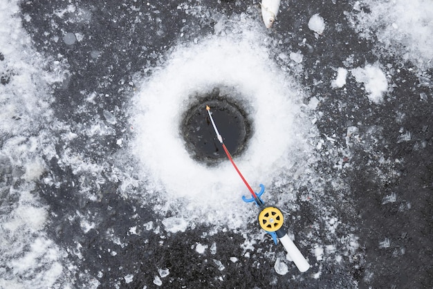 Winterangelrute zum Eisangeln in der Nähe des Lochs liegt im Schnee Winterangeln