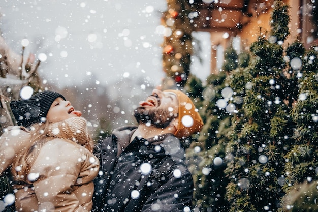 Winterferien und Personenkonzept Glücklicher Vater und kleine Tochter wählen Weihnachtsbaum auf dem Straßenmarkt Auswahl und Kauf eines Weihnachtsbaums auf dem Weihnachtsmarkt