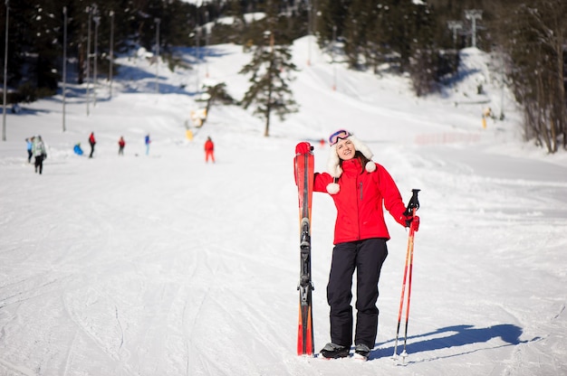 Winterferien- und Sportkonzept mit Abenteuerfrau mit Skiern in ihren Händen am Fuße des Berges.