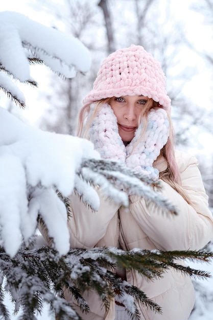 Winterfrau im Schnee, der Kamera draußen an schneiendem kaltem Wintertag betrachtet Portrait Kaukasisches weibliches Modell draußen im ersten Schnee