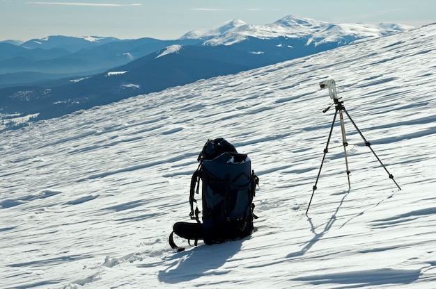 Wintergebirgslandschaft mit Touristenrucksack und Fotostativ