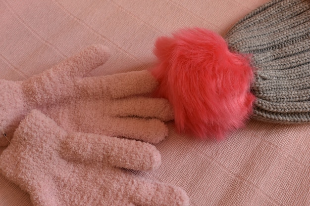 Winterhandschuhe und eine Mütze auf rosa Hintergrund