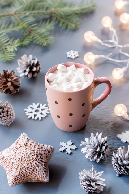 Winterhintergrund mit heißem Getränk mit Marshmallows, Weihnachtsbeleuchtung, Tannenbaum und Dekorationen. Platz kopieren, Ansicht von oben