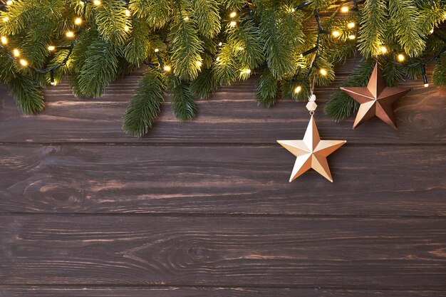 Winterhintergrund mit Tannenzweigen und Weihnachtsschmuck in Form von Stern auf Holzkulisse.