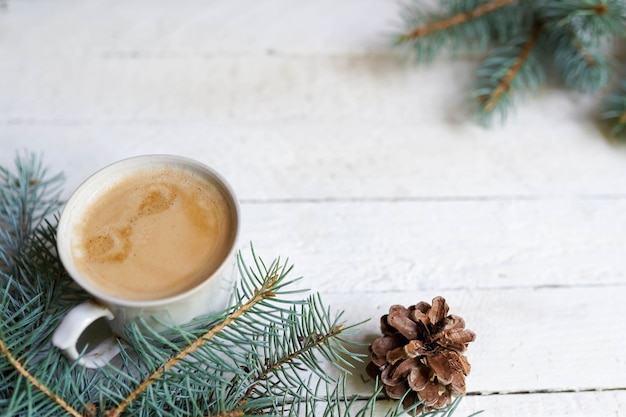 Winterkarte. Kaffeetasse und Kiefer auf weißem hölzernem, Kopienraum