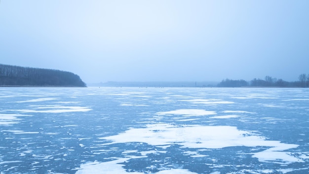 Winterlandschaft auf einem zugefrorenen Fluss bei Sonnenuntergang schwerer Frost und ein zugefrorener Fluss im Winter ist alles mit Schnee bedeckt