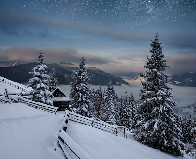 Winterlandschaft. bergdorf in den ukrainischen karpaten. lebendiger nachthimmel mit sternen und nebel und galaxie. deep sky astrophoto.