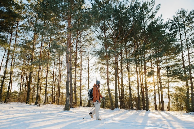 Winterlandschaft ein Mann mit Rucksack und warmer Winterkleidung im Wald, der in den Bergen unterwegs ist