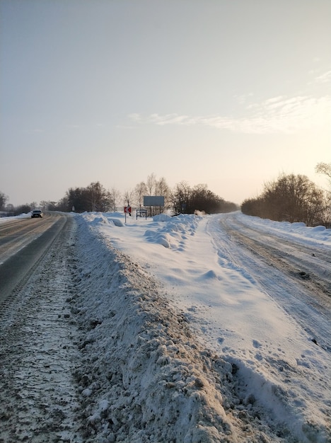 Winterlandschaft. Eine mit weißem Schnee bedeckte Straße. Das Auto fährt die Straße entlang.