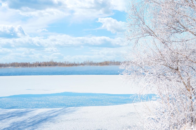 Winterlandschaft gefrorener See, verschneiter Wald und schöner bewölkter Himmel.