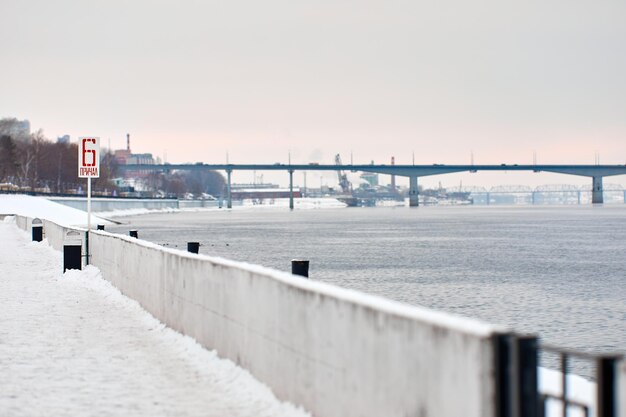 Winterlandschaft mit Brücke über den zugefrorenen Fluss Schild Liegeplatz Nr. 6 Perm Russland Kama-Fluss