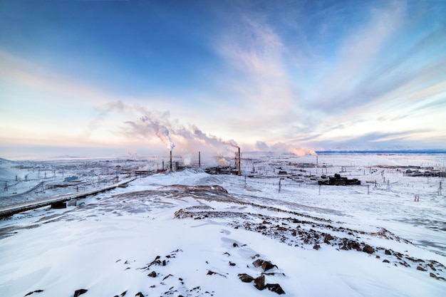 Winterlandschaft mit den rauchenden Pfeifen von Stahlwerken