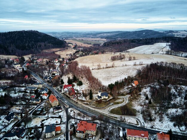 Winterlandschaft mit Dorf in der Nähe von Bergen