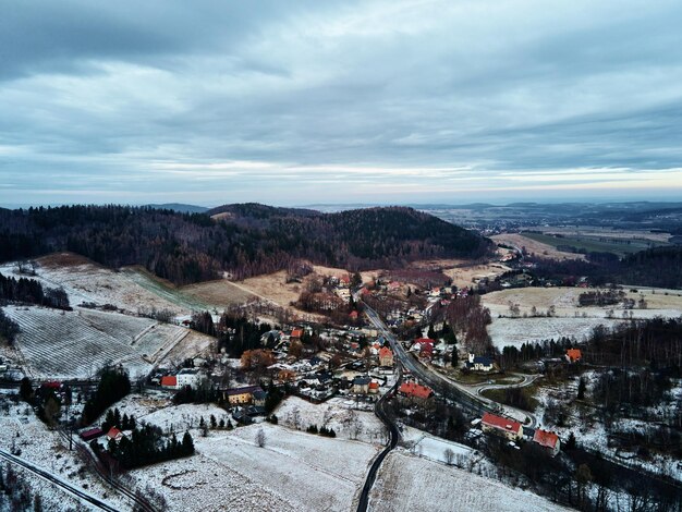 Winterlandschaft mit Dorf in der Nähe von Bergen