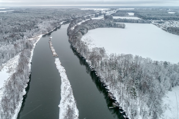 Winterlandschaft mit einem Fluss, der durch den Winterwald fließt.